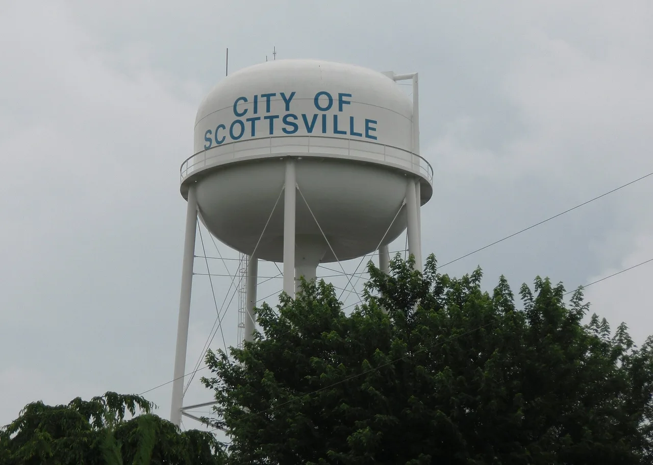 The Scottsville water tower, lettered CITY OF SCOTTSVILLE, standing above the treetops under a grey sky.